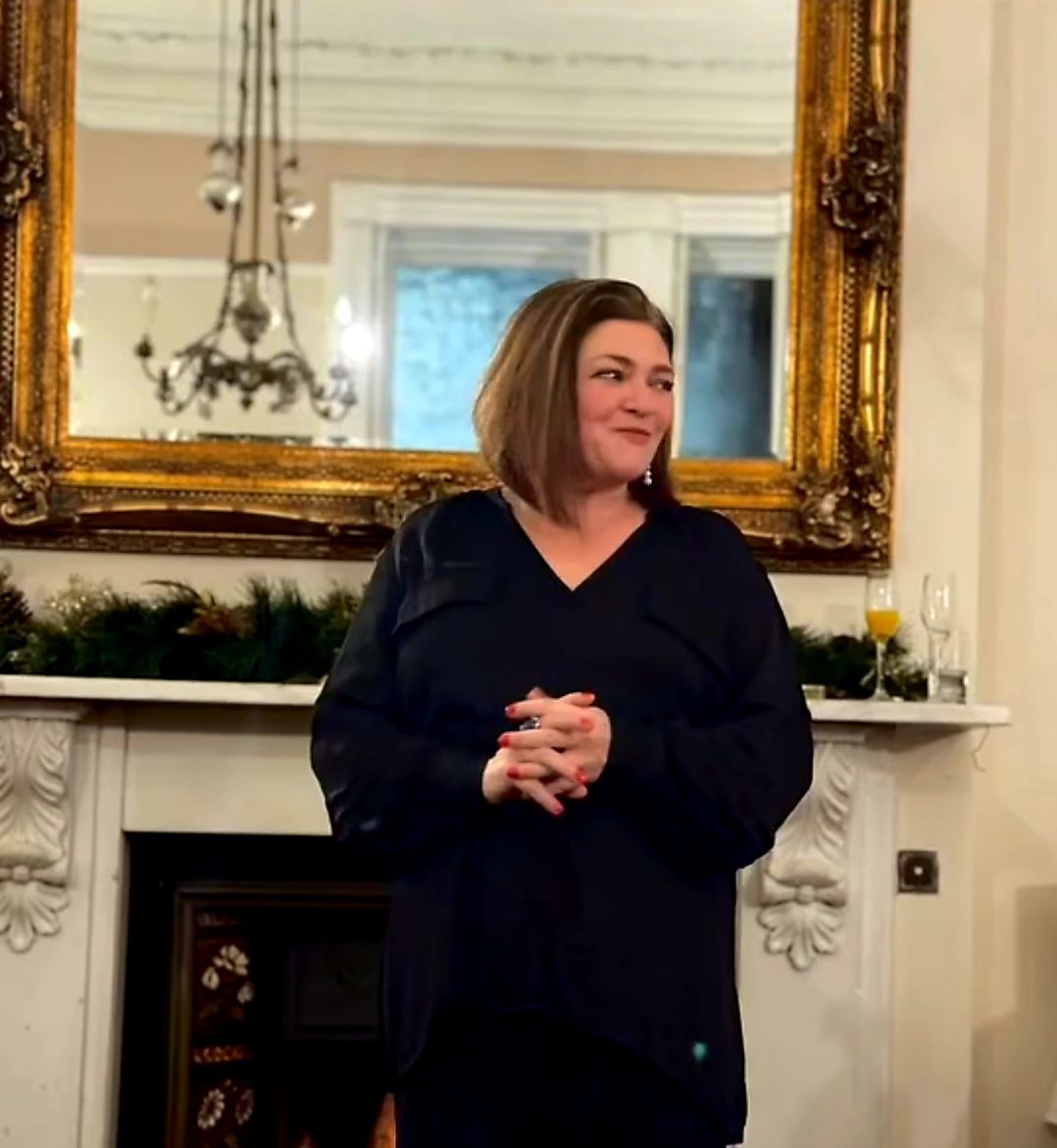 Nikki speaking to guests at a public event in front of a gilded mirror