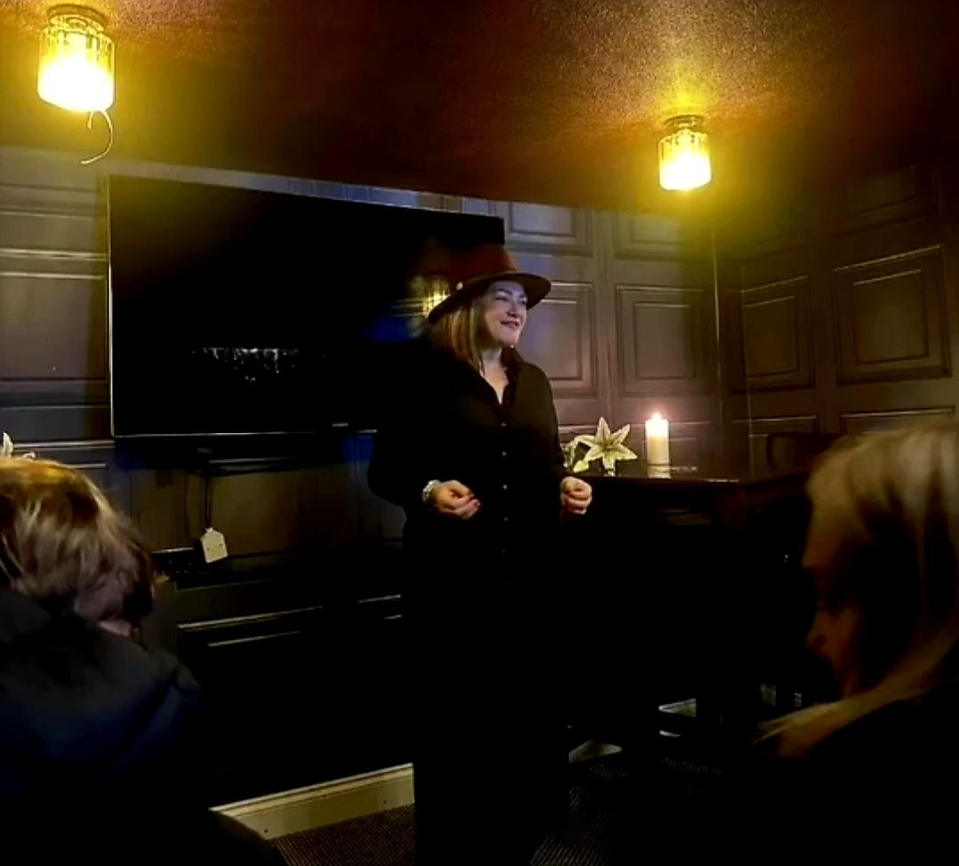 Nikki giving readings to an audience in a candlelit venue