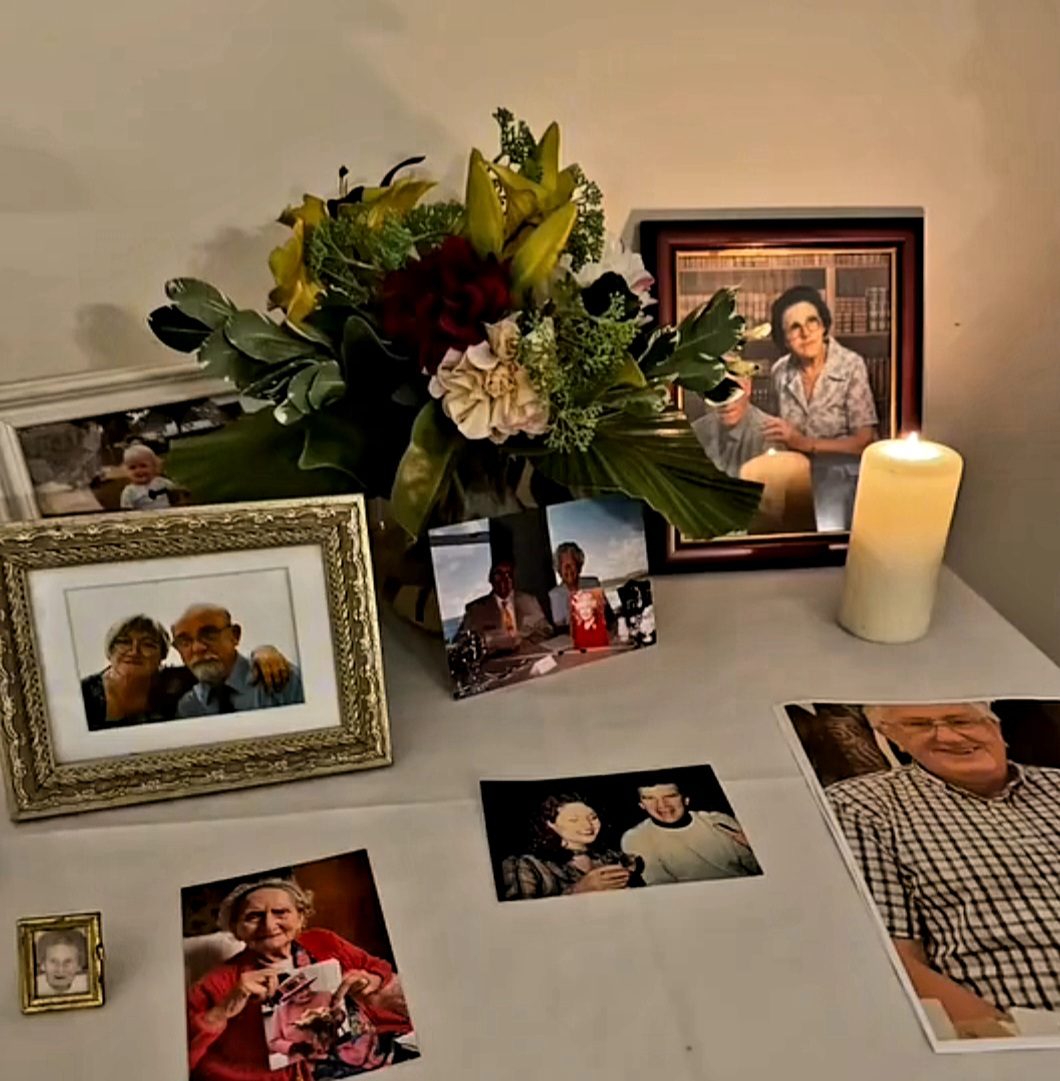 Photos of loved ones, flowers and a candle set out at a mediumship evening