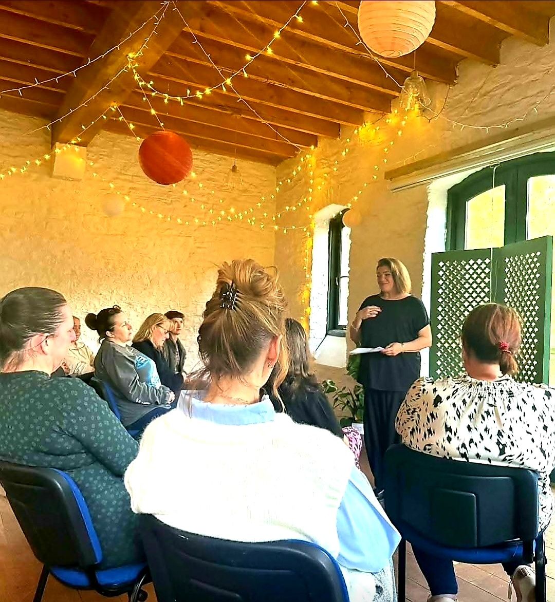 Nikki speaking to a group in a barn strung with fairy lights