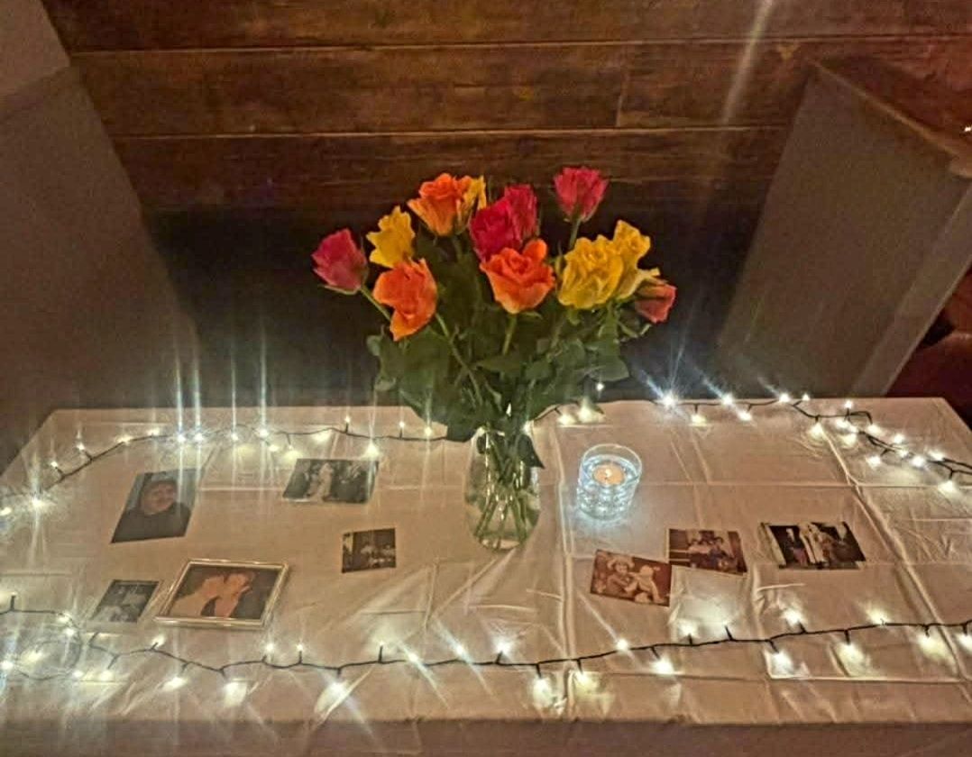 Photos of loved ones with roses and fairy lights at a mediumship evening