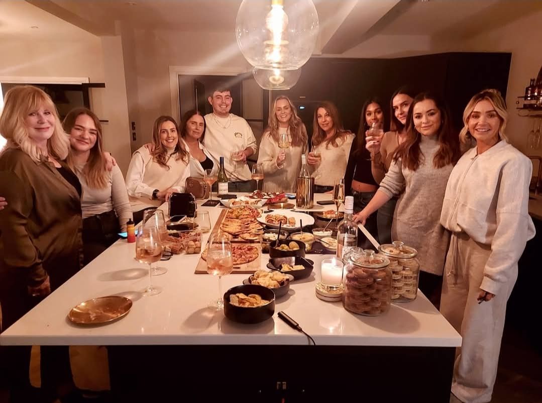 Guests around a kitchen island with food and wine at an evening with Nikki